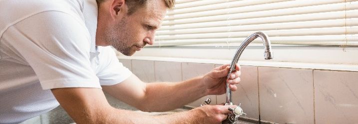Mann repariert Wasserhahn an Spüle in Küche
